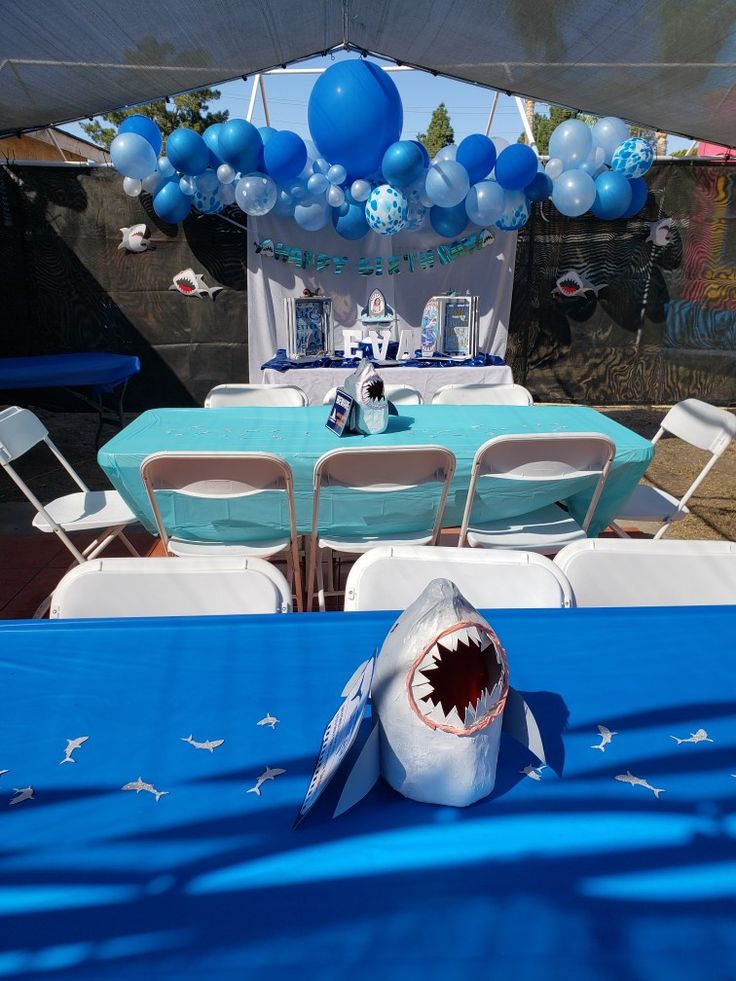 a party table with blue balloons and shark decorations