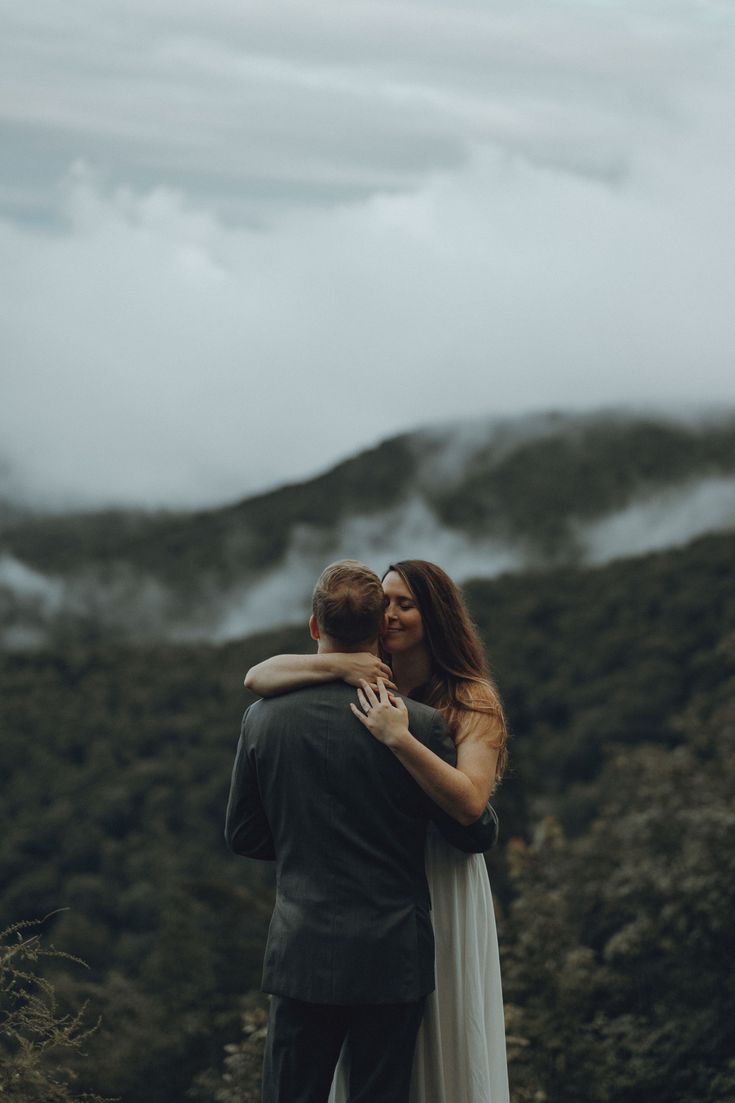 a bride and groom embracing in the mountains