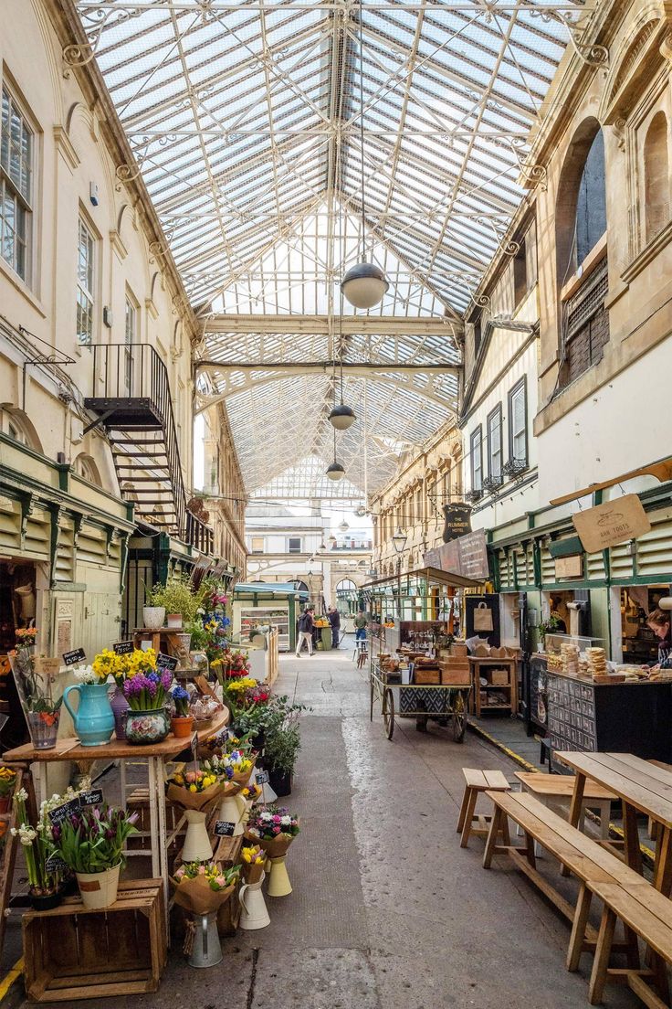 an indoor market with lots of plants and flowers on the tables in front of it