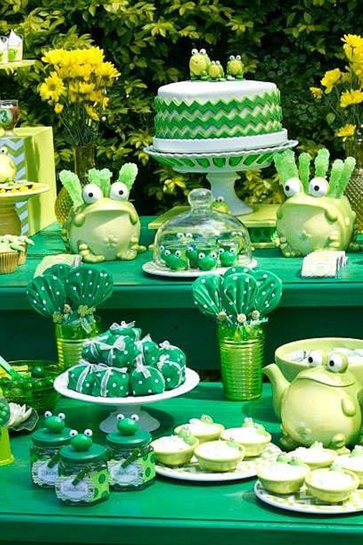 a green table topped with lots of cakes and cupcakes