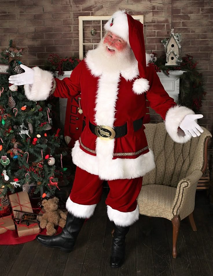 a man dressed as santa claus standing next to a christmas tree