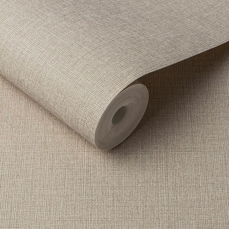 a roll of beige fabric on top of a white tablecloth with a rolled up piece of paper next to it