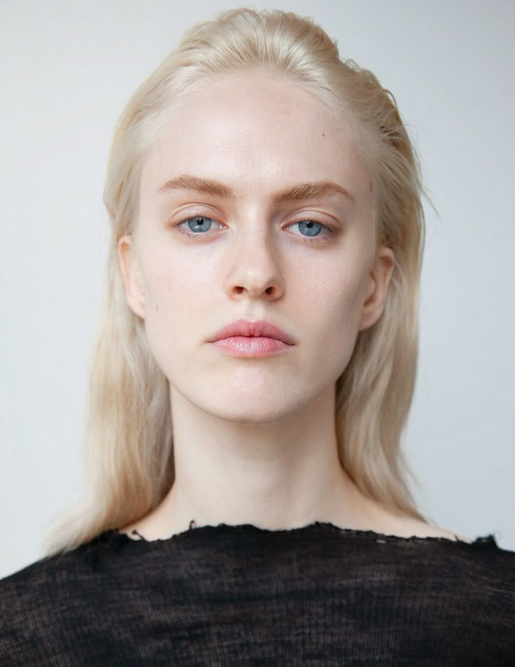 a woman with blonde hair and blue eyes is looking at the camera while wearing a black top