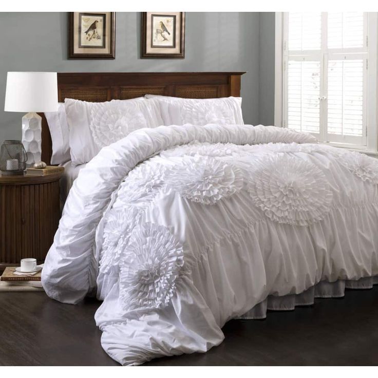 a bed with white comforter and pillows in a room