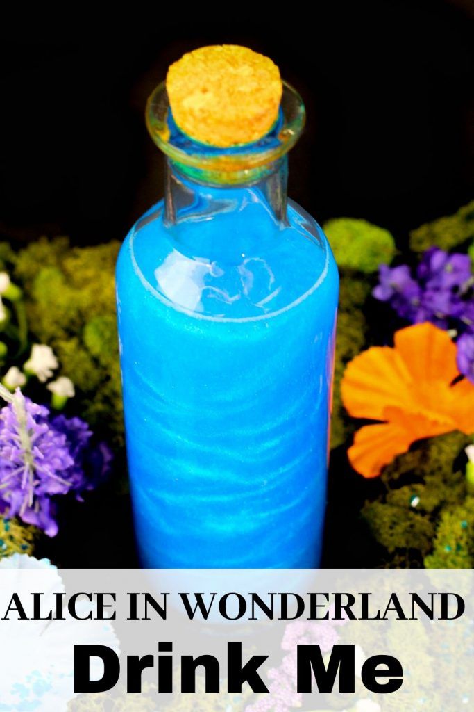 a blue bottle sitting in front of flowers with the words alice in wonderland drink me