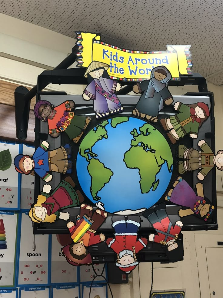 a clock with children around the world hanging from it's side in a classroom