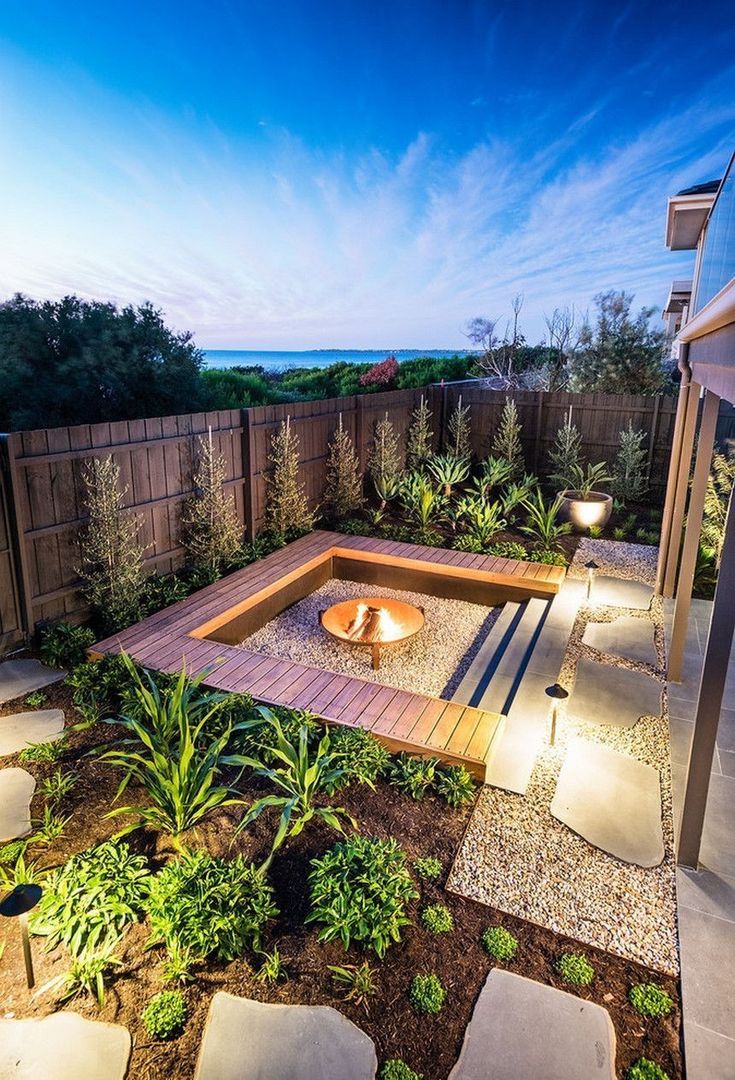 an outdoor fire pit surrounded by plants and rocks