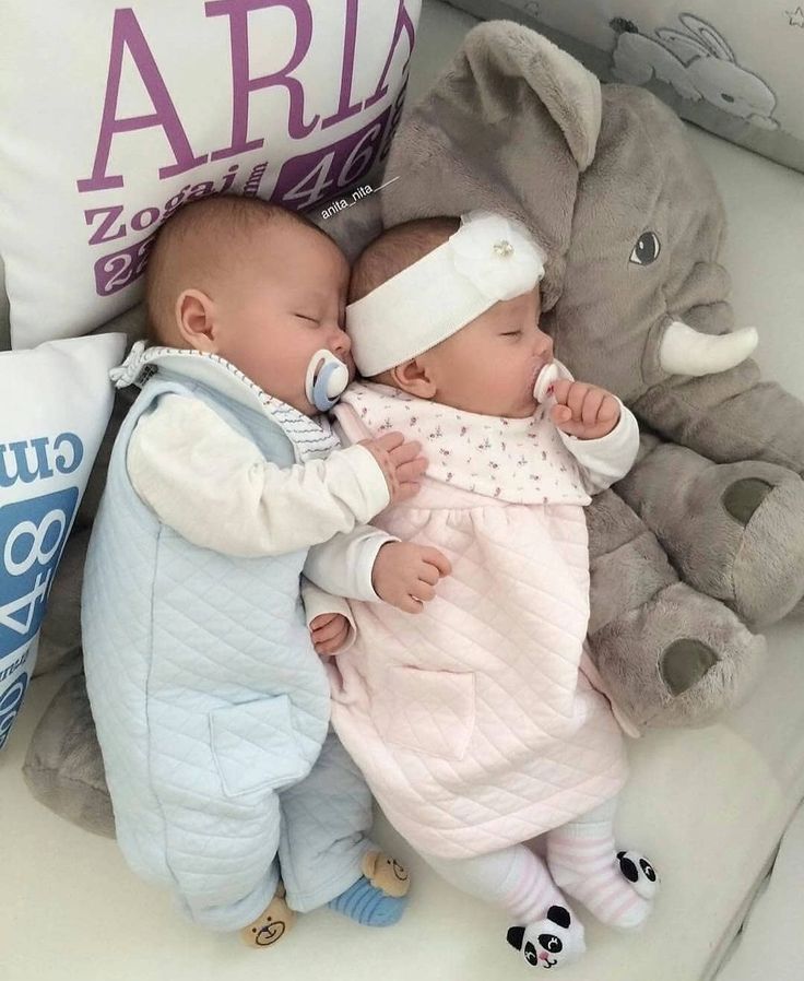 a baby sleeping next to an elephant with a pacifier in it's mouth