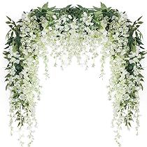 an arrangement of white flowers and greenery is arranged in the shape of a flower arch