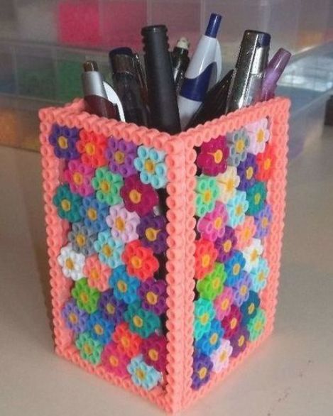 a crocheted pen holder with pens and pencils in it on a table