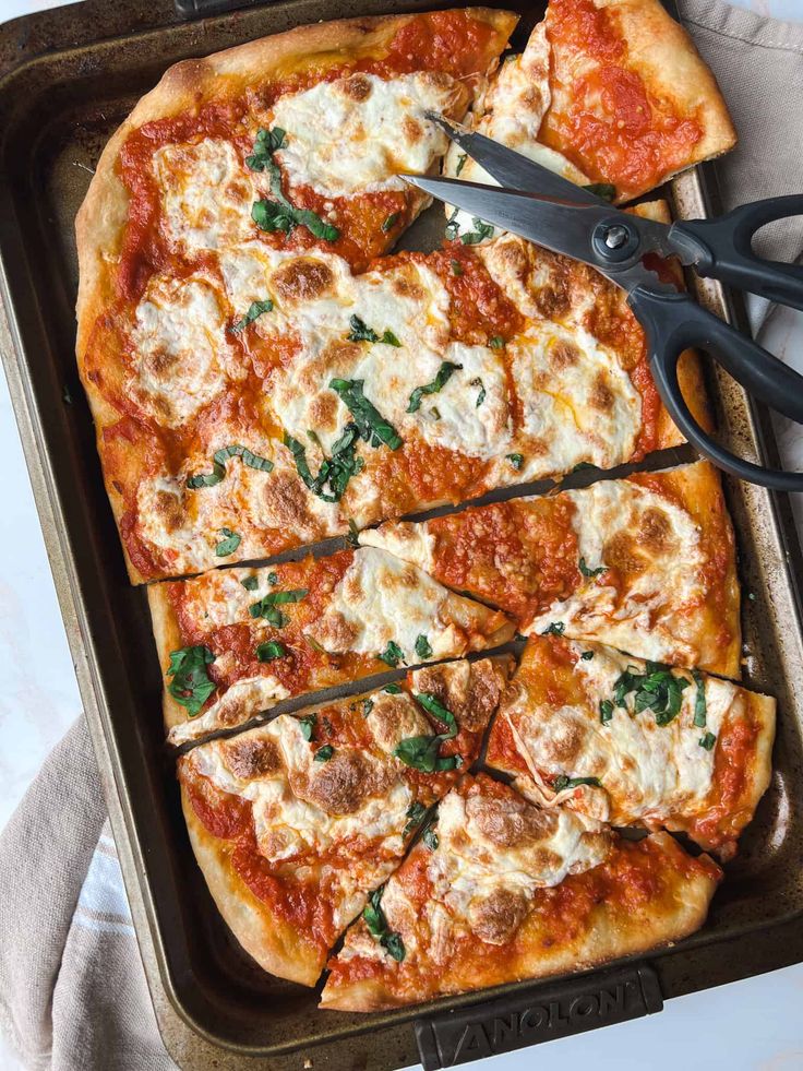 the pizza is cut into slices and ready to be put in the oven with tongs