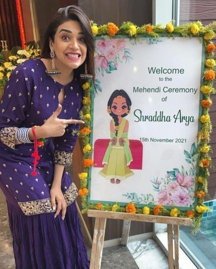 a woman standing in front of a sign that says welcome to the mehndi ceremony of shraddha arga