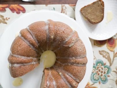 a bundt cake sitting on top of a white plate next to slices of bread