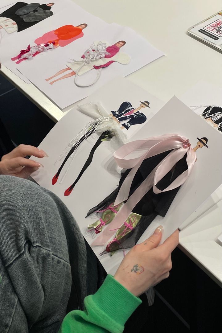 a woman sitting at a table with some paper and scissors