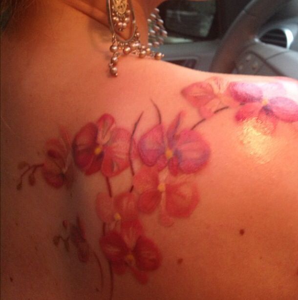 the back of a woman's shoulder with pink flowers painted on it and pearls around her neck