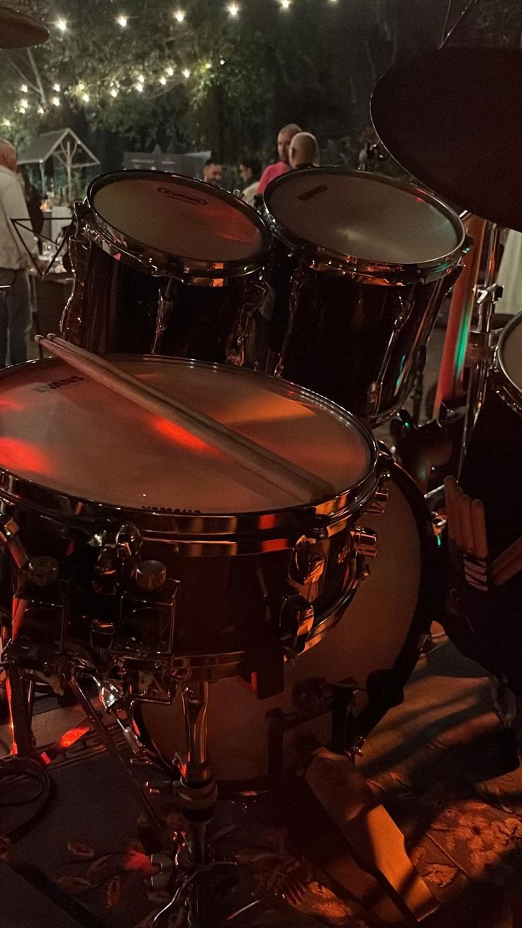 a group of people standing around a drum set