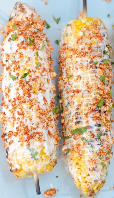 three corn on the cob covered in cheese and seasoning