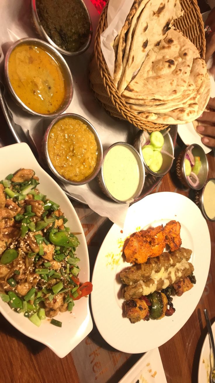 a table filled with different types of food on plates next to bowls and utensils