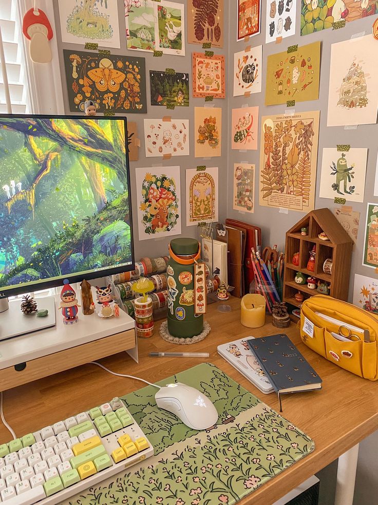 a desk with a computer monitor, keyboard and various pictures on the wall behind it