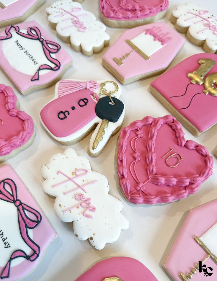 pink and white decorated cookies are arranged on a table with gold scissors, keys, and other decorative items