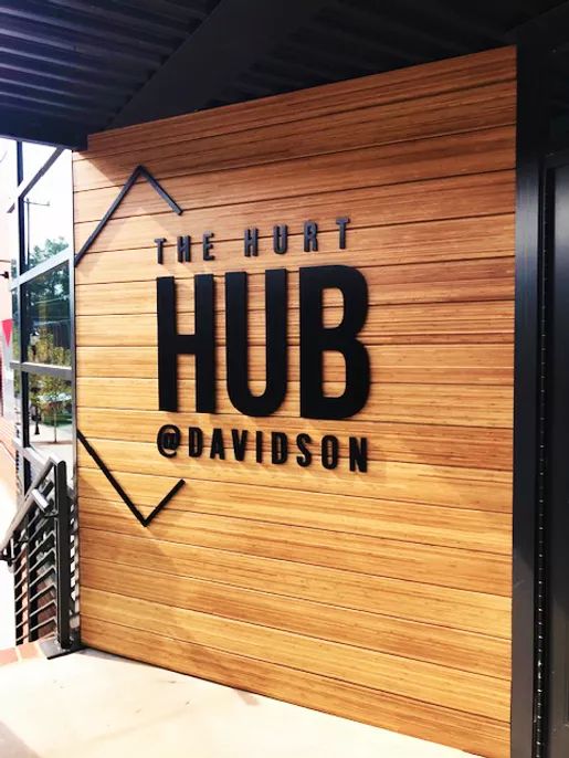 the entrance to the hub davidson building is made out of wood and has black lettering on it