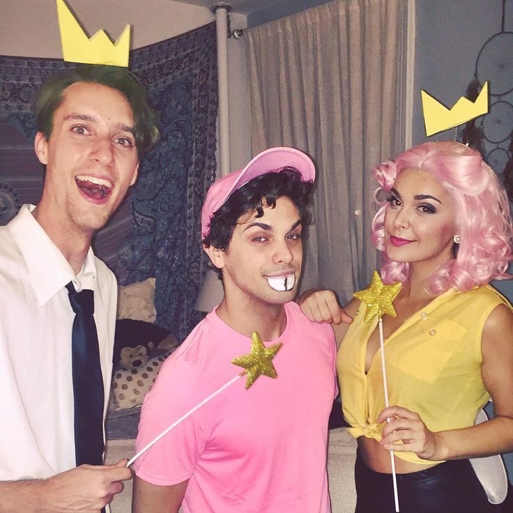 two men and a woman dressed in costumes pose for a photo with one man wearing a pink wig