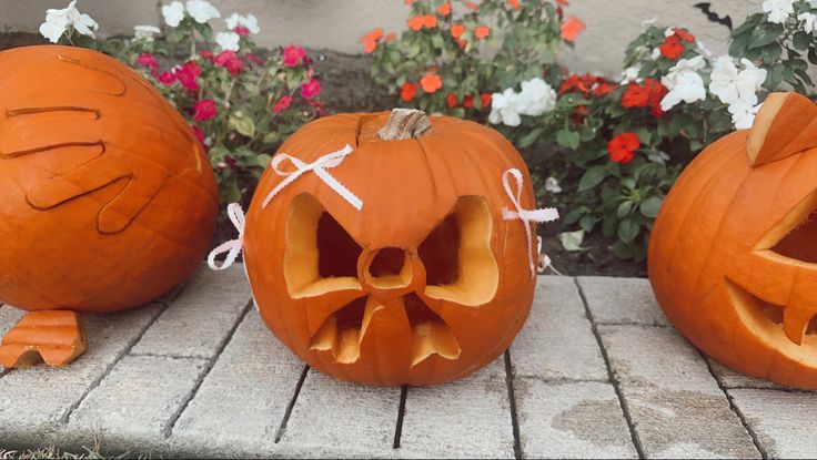 three carved pumpkins sitting on top of a brick walkway