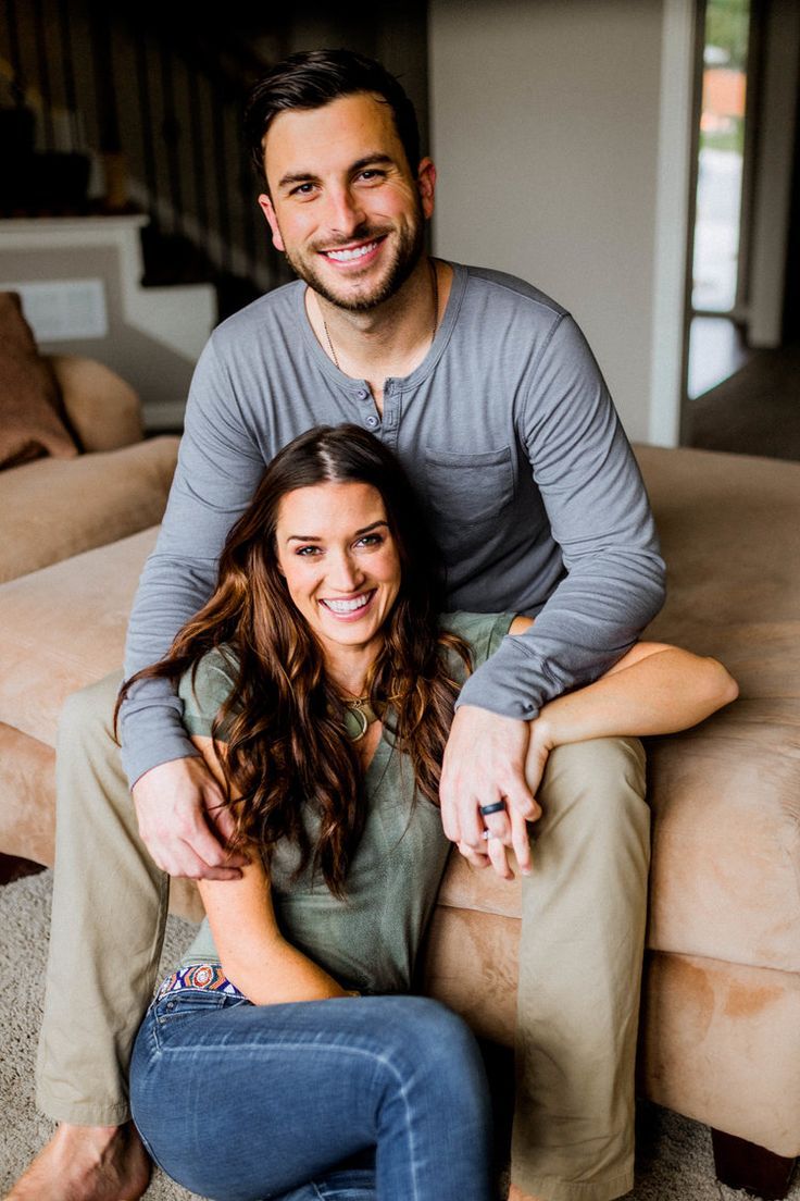 a man and woman sitting on top of a couch in front of a beige couch