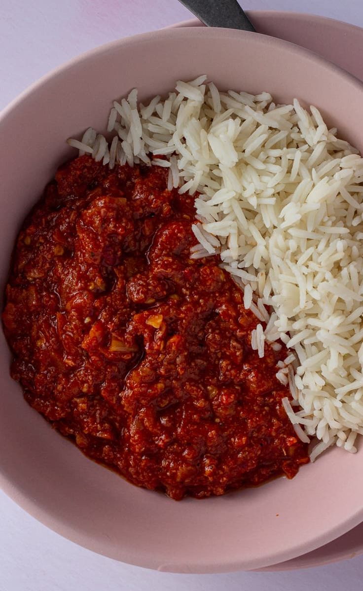 two bowls filled with rice and red sauce