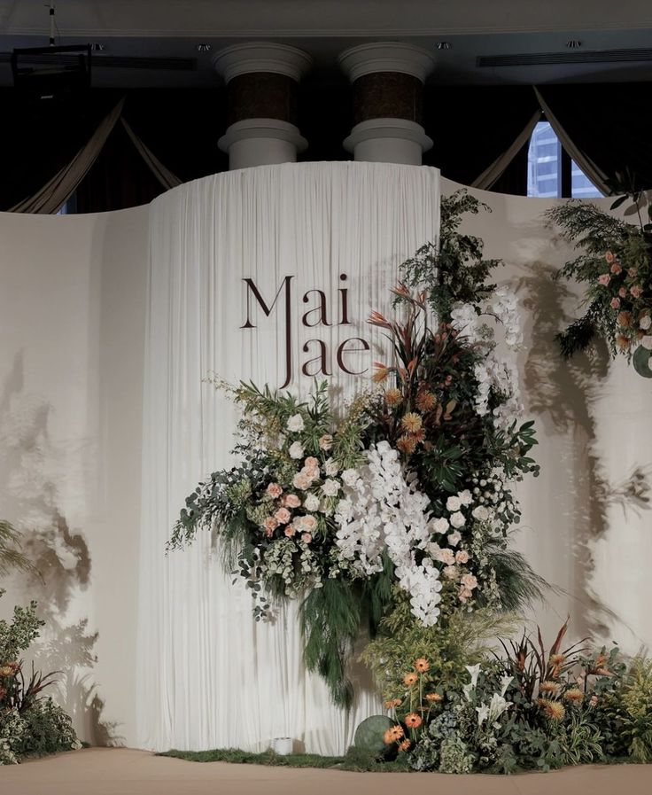 a floral display on the side of a wall with flowers and greenery hanging from it's sides