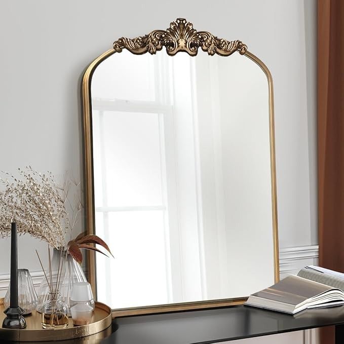 a mirror sitting on top of a black table next to a vase with flowers in it