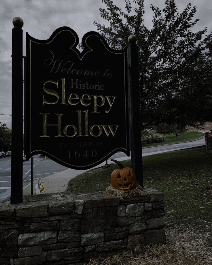 a welcome sign for sleepy hollow with a carved pumpkin on the front and side of it