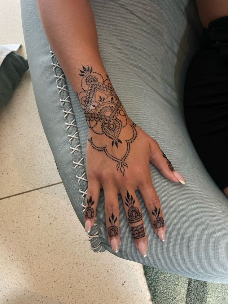 a woman's hand with henna tattoos on her left arm and right hand