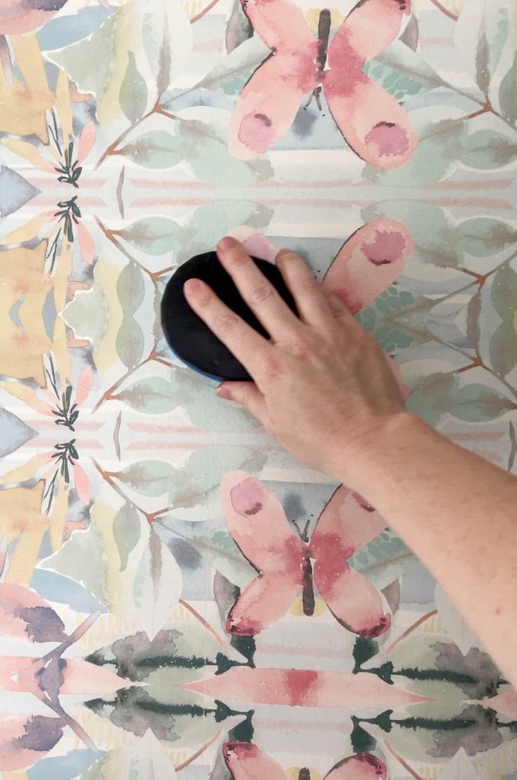 a person's hand holding a mouse on top of a colorful wallpaper