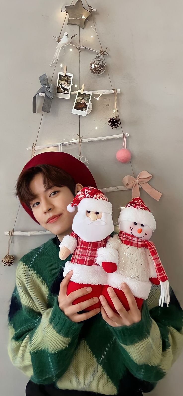 a boy holding two stuffed animals in front of a christmas tree