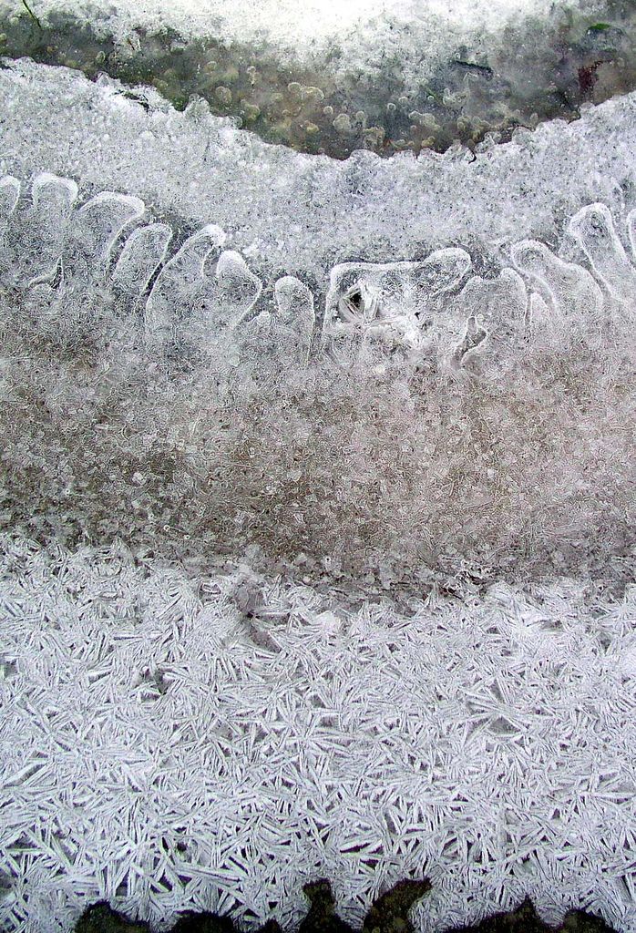 an aerial view of the surface of ice and water with snow flakes on it