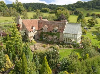 an aerial view of a large house surrounded by trees and bushes in the country side