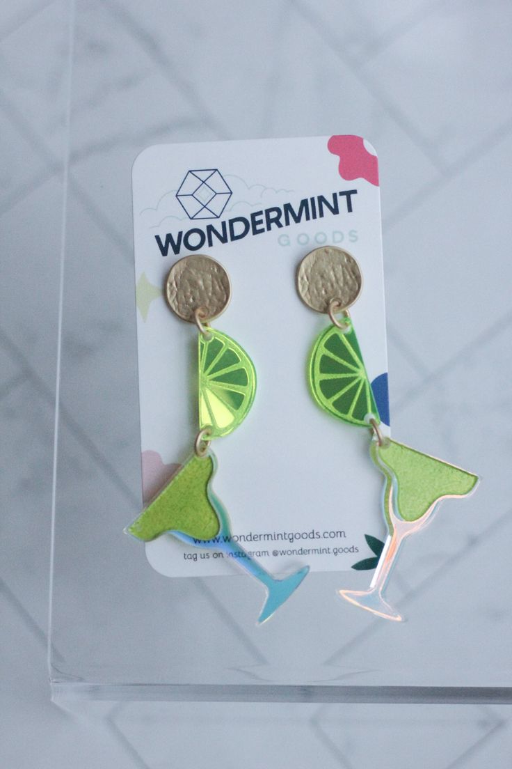 a pair of earrings with lime slices and coins hanging from it's earwires