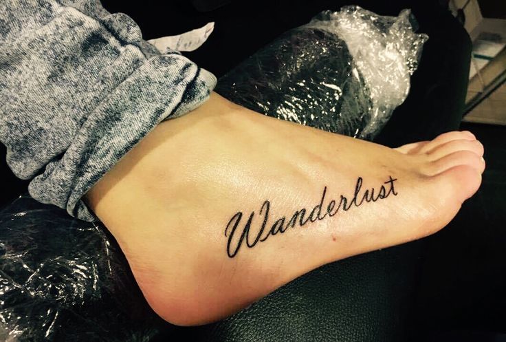 a woman's foot with the word wanderlust tattooed on her left side