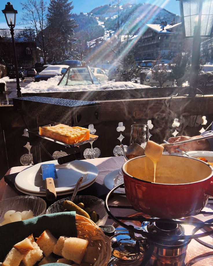 a table topped with plates and bowls filled with food next to a snow covered mountain