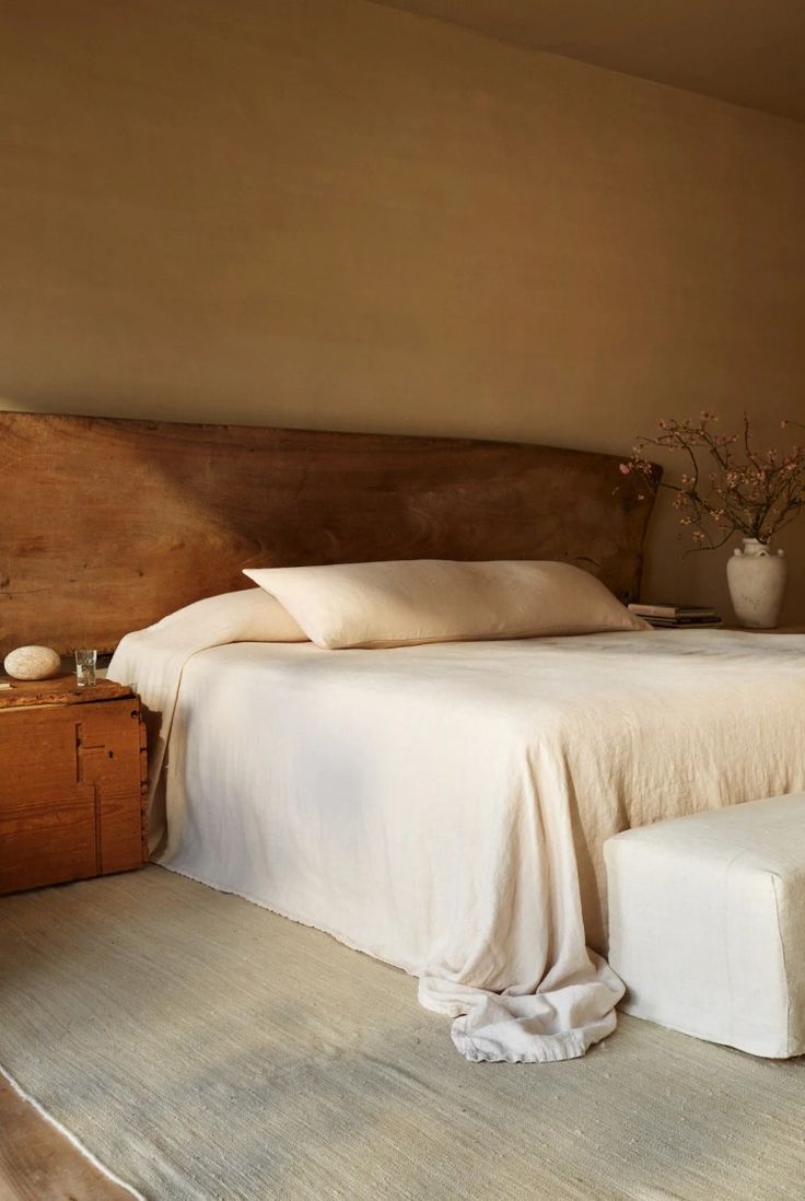 a large bed sitting next to a wooden dresser in a bedroom with white sheets and pillows