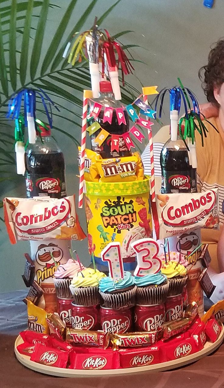 a young boy sitting next to a giant cake with candy on it and confections