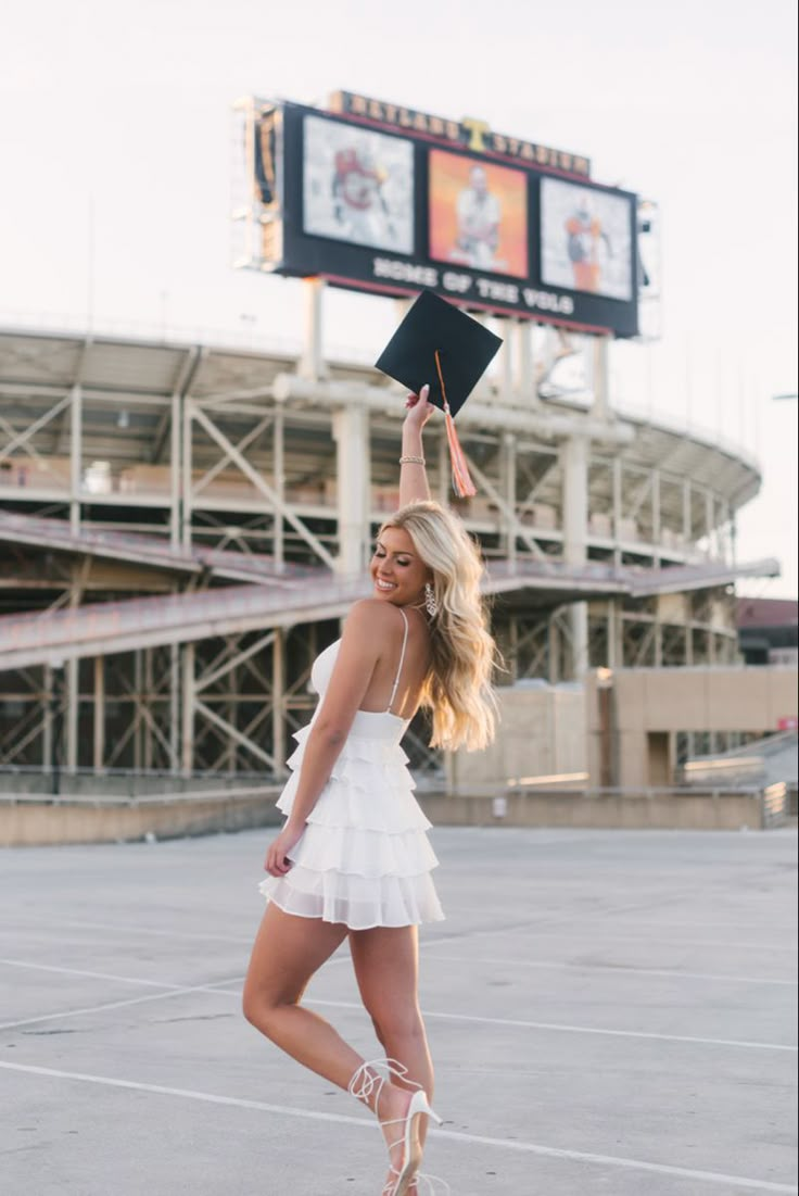 a woman in a white dress is holding up a black book and posing for the camera