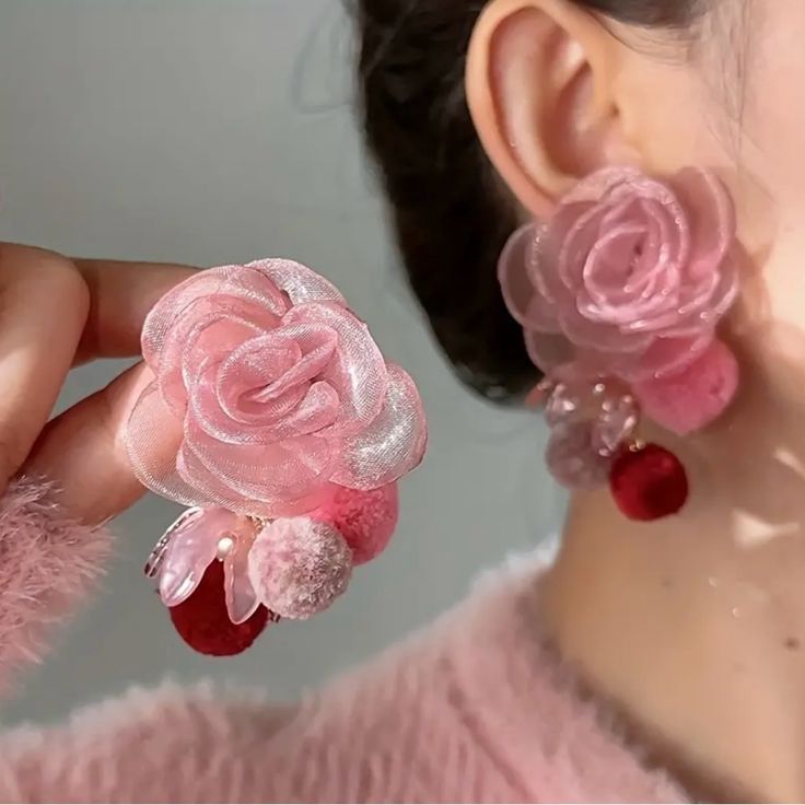 a close up of a person wearing pink earrings with flowers on the front and back