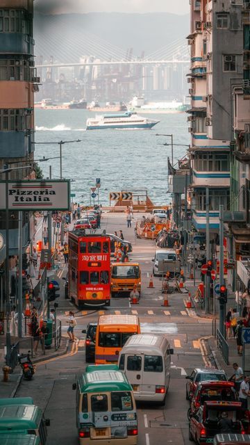 a city street filled with lots of traffic next to tall buildings and a bridge in the background