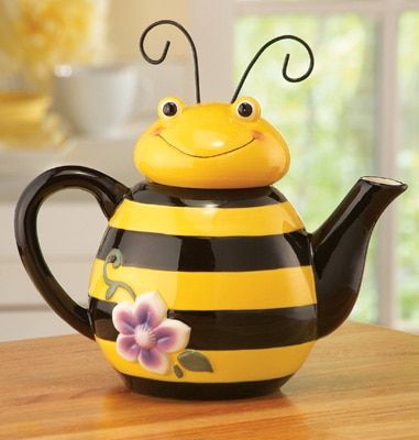 a yellow and black bee teapot sitting on top of a wooden table