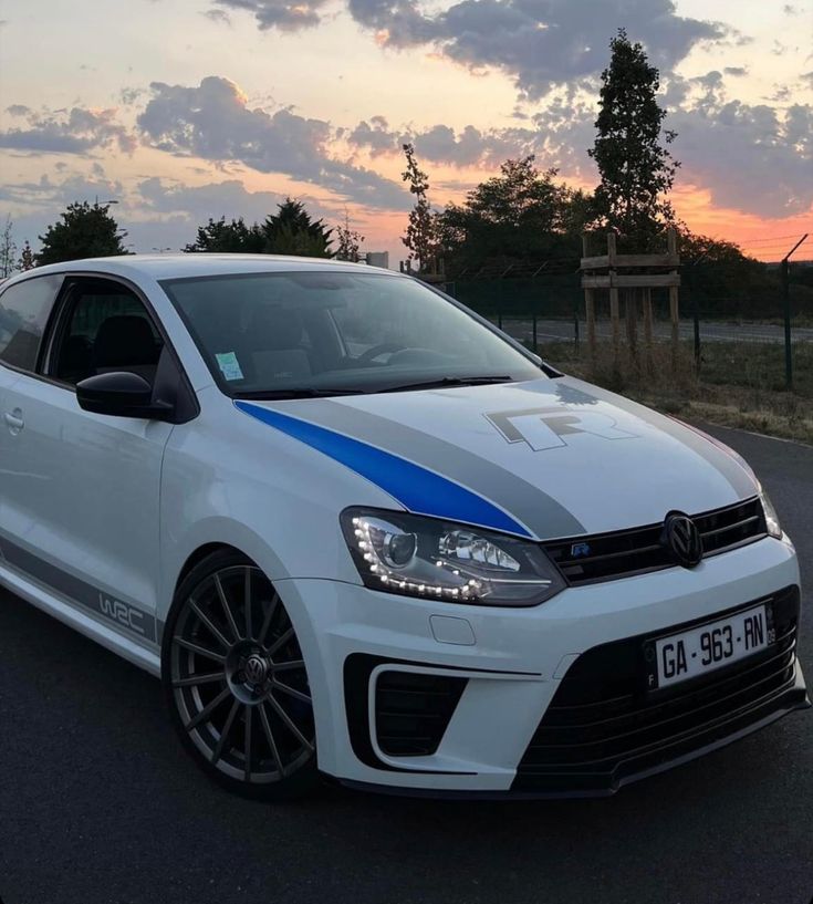 a white car with blue stripes parked on the street