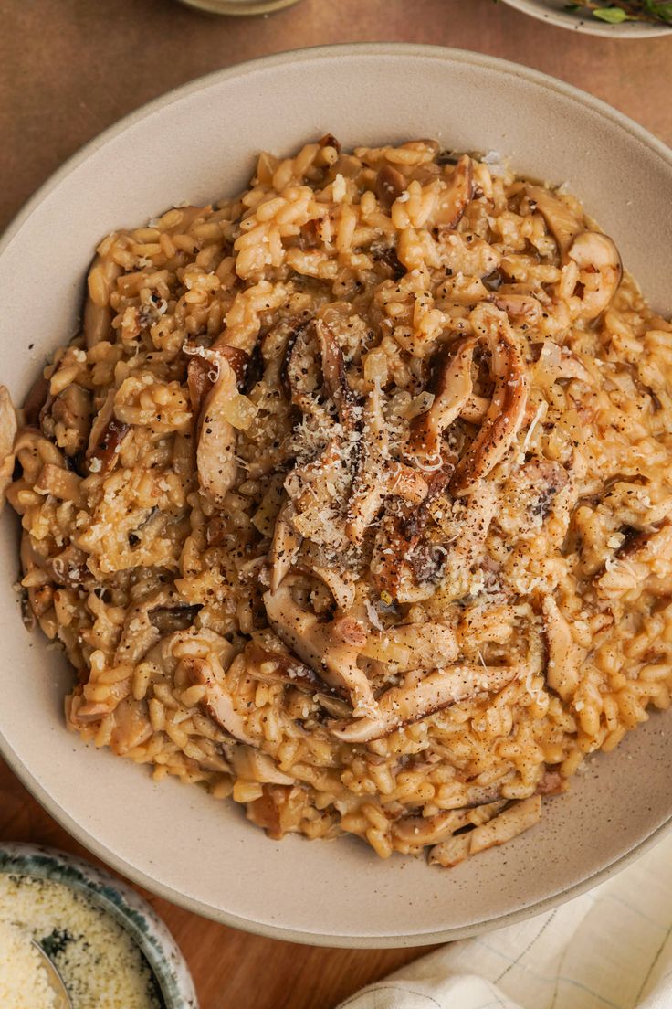 a bowl filled with rice and meat on top of a wooden table next to other dishes