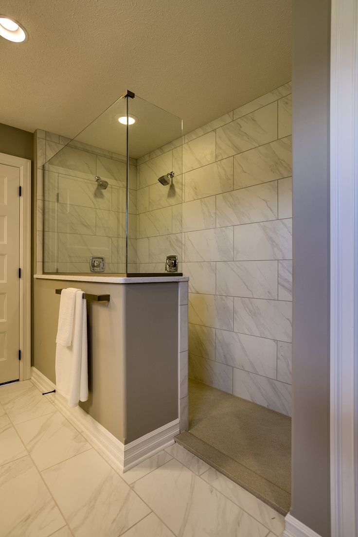 a bathroom with a sink, mirror and shower in it's center wall next to a door