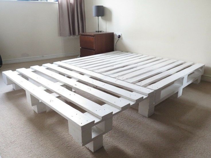 a bed frame made out of pallets in a room with carpeted flooring